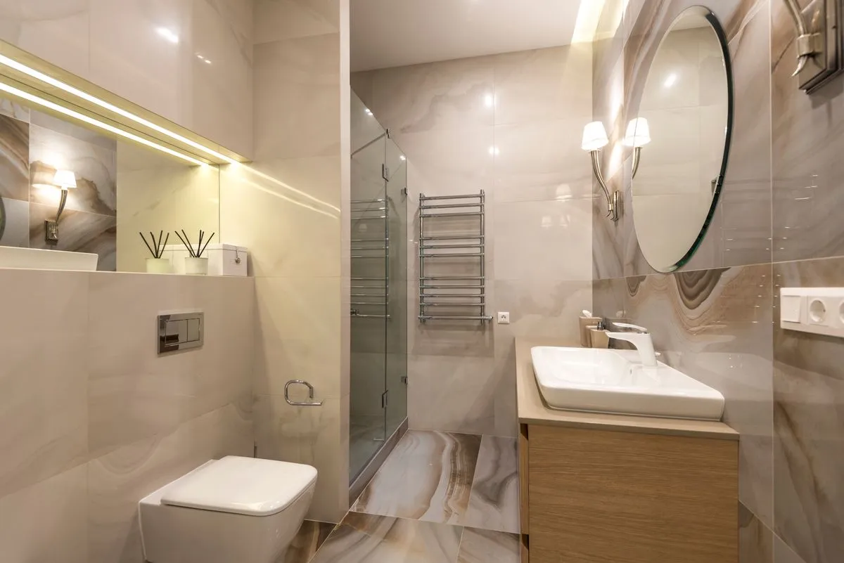 Baño remodelado con revestimiento símil mármol y box de ducha de vidrio