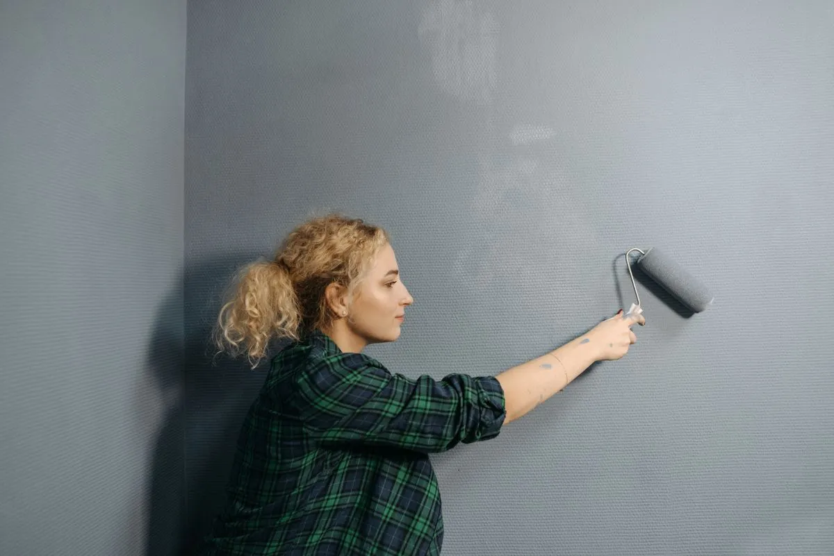 Pintor aplicando pintura con rodillo en una pared interior